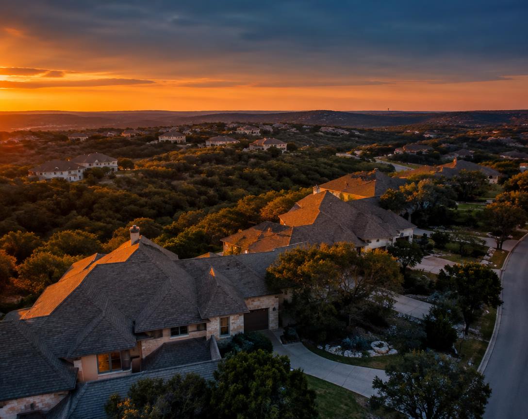 Hill-country neighborhood rooftops at dusk